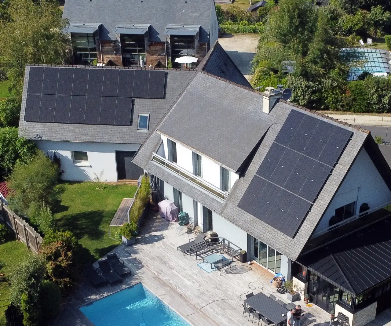 Vue aérienne d'une maison équipée de panneaux solaires avec piscine, installation réalisée par Alvea Solaire